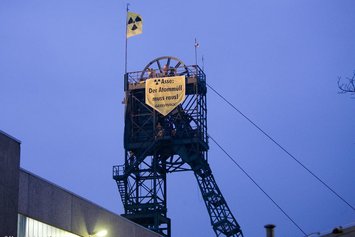 Auf einem Förderturm aus Stahl hängt ein Transparent von Greenpeace mit dem Text "Asse: Der Atommüll muss raus!"