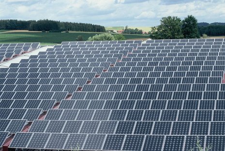 Solaranlage mit zahlreichen Solarmodulen vor einer Naturlandschaft