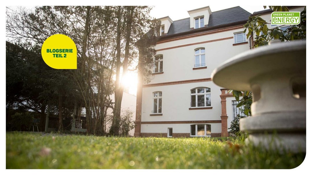 Eine alte Villa umgeben von grüner Wiese. Die Perspektive ist von unten, von der Wiese aus.