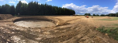 Rundliche Baugrube vor Waldgebiet