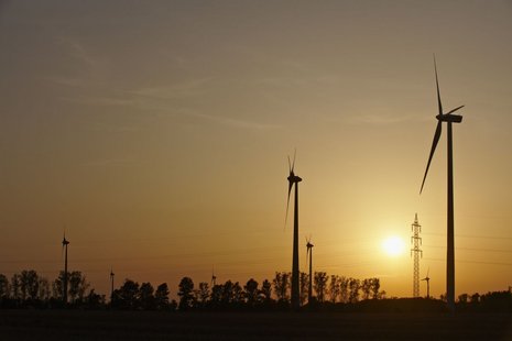 Vier Windkraftanlagen von unten gegen das Licht bei Sonnenuntergang aufgenommen.