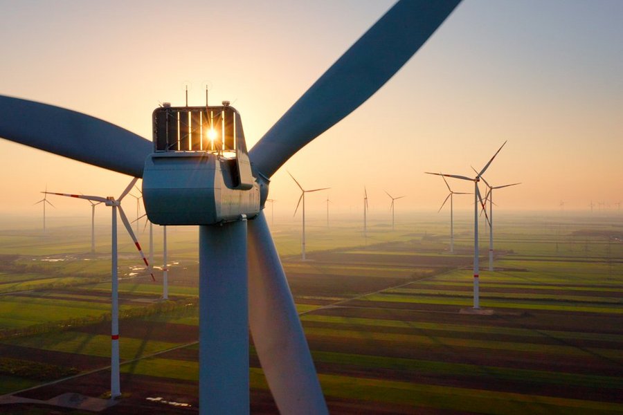 Windräder im Sonnenuntergang über einem Feld.