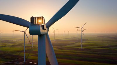 Windräder im Sonnenuntergang über einem Feld.