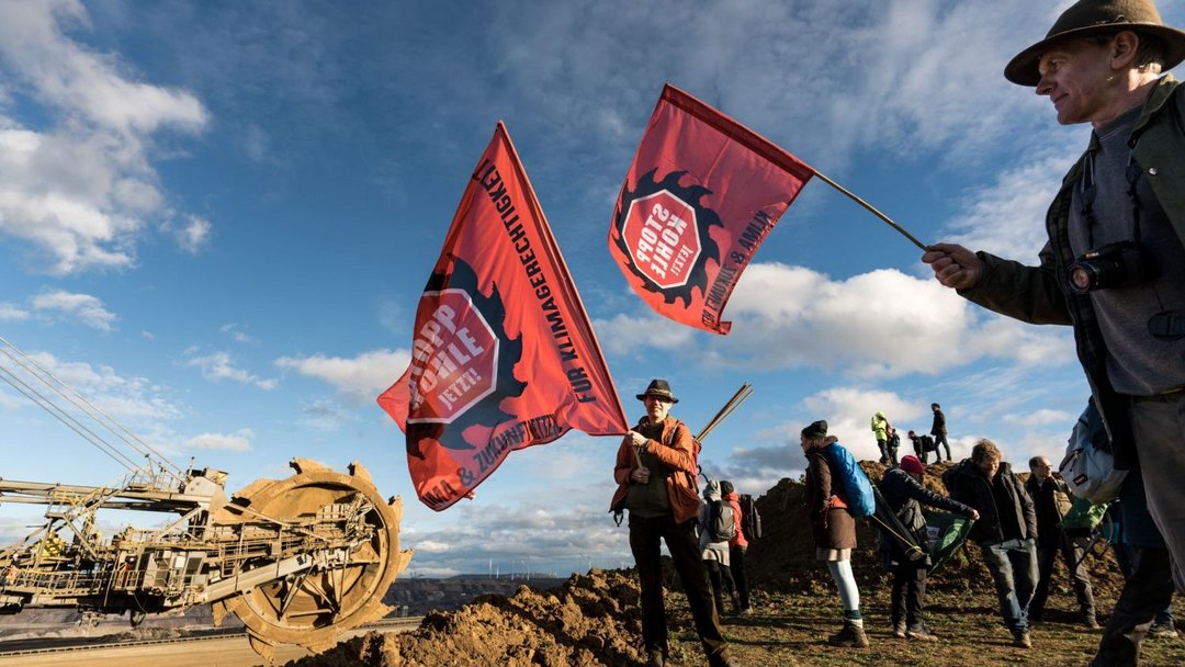 Eine Gruppe demonstrierender Menschen an der Abbruchkante des Braunkohlerevier Lützeraths.