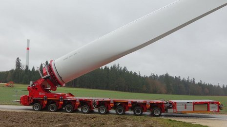 Transport eines Rotorblatts für Windkraftanlagen auf rotem Fahrzeug