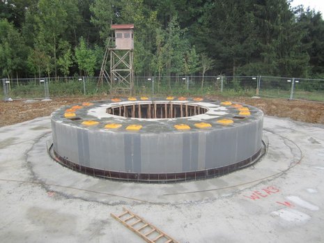 Rundlicher Fundamentbau vor Waldgebiet