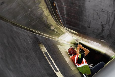 Arbeiter schließt Kabel im Inneren eines Windradflügels an.