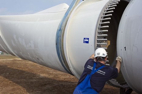 Arbeiter richtet das Flügelblatt am Rotor aus.