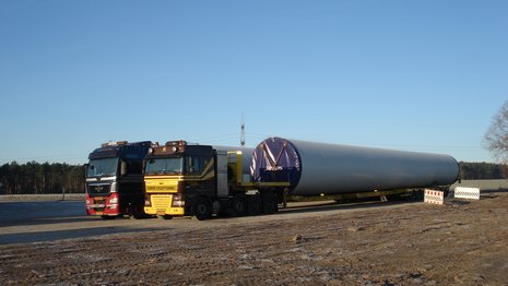 Zwei LKW transportieren jeweils ein langes Turmelement