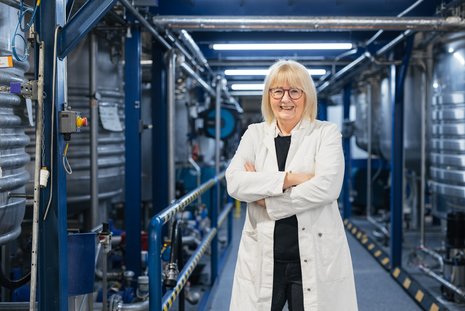 Kundin von Green Planet Energy in weißem Kittel und mit Brille blickt in die Kamera