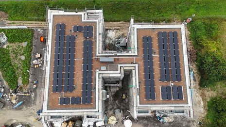 Flachdach mit vielen in Reihen angeordneten Photovoltaikmodulen.