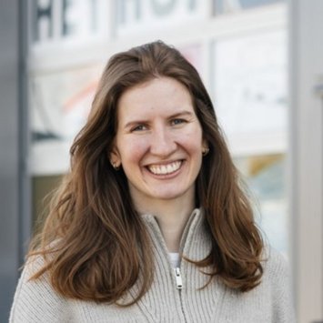 Eine Frau mit langen braunen Haaren lächelt in die Kamera.