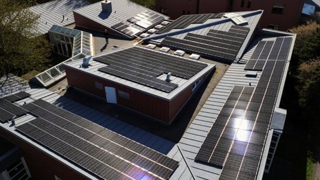 Luftaufnahme eines größeren Hauses, dessen Dach komplett mit Solarmodulen belegt ist.