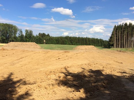 Ausgehobene Erde vor einem Waldgebiet