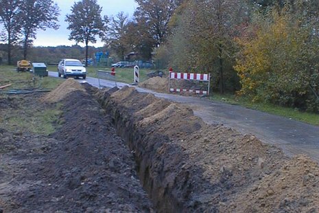 Eine Straße, neben der ein Graben in den Boden gegraben wurde.