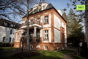 Freistehende Altbau Villa mit gelben Störer und der Aufschrift "Blogserie Teil 7". Oben rechts ist das Logo von Green Planet Energy in Saftgrün abgebildet.
