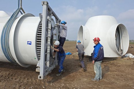 4 Arbeiter arbeiten an der Montage eines Windradflügels.