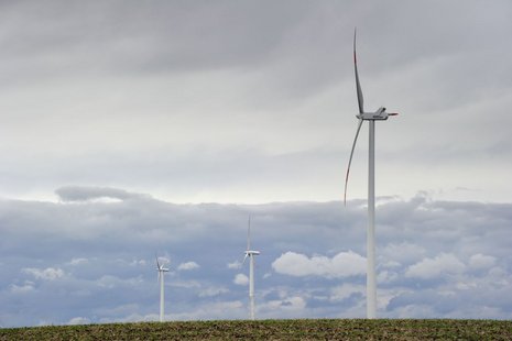 Aufnahme von unten von drei Windturbinen auf einem Feld.