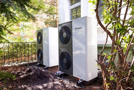 Zwei große Vaillant-Wärmepumpen im Garten vor einem Altbau.