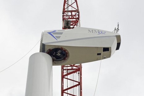 Der Rotor einer Windkraftanlage wird mit einem Kran auf den Mast montiert.